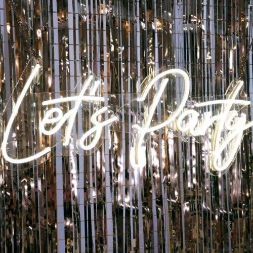 lets party neon sign on silver backdrop