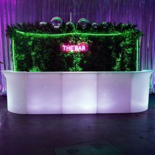 neon pink sign the bar on a greenery wall
