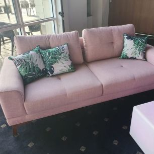 two seater pink couch with tropical pillows 