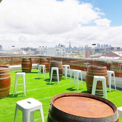 White Bar Stools around wine barrels on a turf roof top 