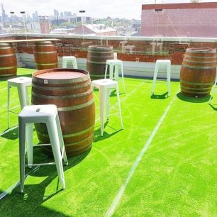 wine barrels and white stools on turfed rooftop