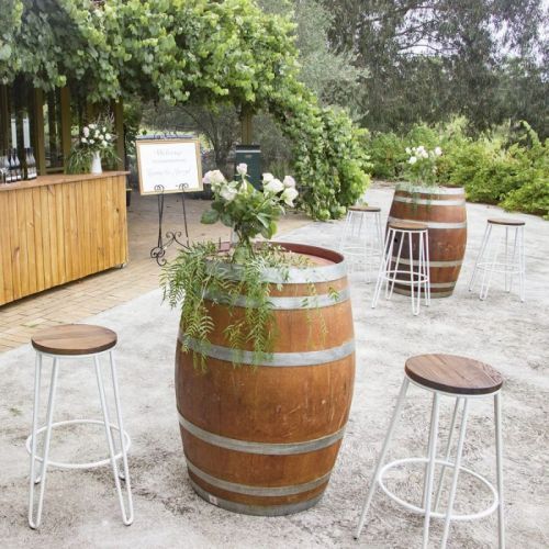 wine barrels amd white hairpin stools at rustic wedding